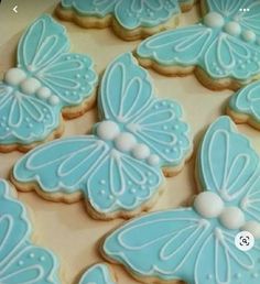 decorated cookies in the shape of butterflies on a table with white frosting and blue icing