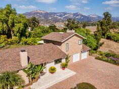 an aerial view of a house with mountains in the background and palm trees on either side