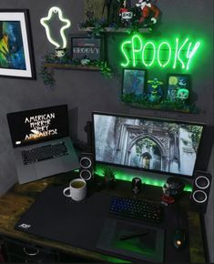 a desk with a laptop, keyboard and monitor lit up by neon signs on the wall