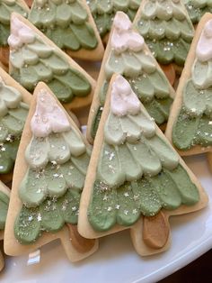 cookies decorated with green and white icing are on a plate in the shape of christmas trees