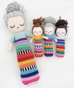 three crocheted dolls sitting next to each other on a white surface with their eyes closed