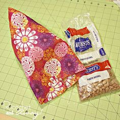 two pieces of fabric sitting on top of a cutting board next to a bag of nuts