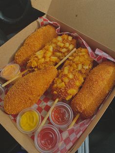 an open box filled with fried food and dipping sauces