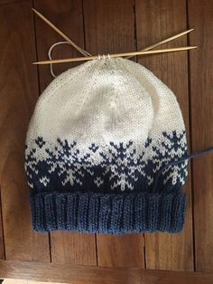 a white and blue knitted hat hanging on a wooden wall