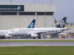 two large passenger jets sitting on top of an airport tarmac next to a building