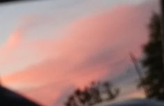 the sky is pink and blue as seen through a car window