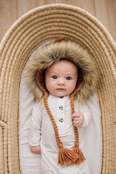 a baby wearing a white outfit and fur hat