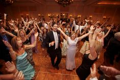 a group of people standing on top of a dance floor with their arms in the air