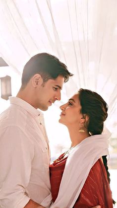 a man and woman standing next to each other under a white drapeed curtain