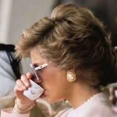 a woman talking on a cell phone while holding a remote control to her ear and wearing sunglasses