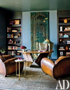 a living room filled with furniture and bookshelves next to a painting on the wall