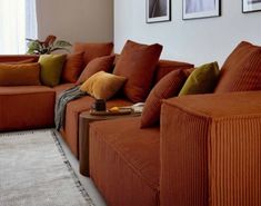 a living room with orange couches and pictures on the wall