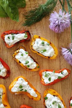 several stuffed peppers with cream cheese and herbs on a wooden table next to flowers,