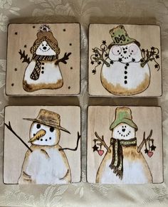 four wooden coasters with snowmen painted on them