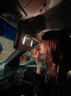 a woman sitting in the passenger seat of a car talking on her cell phone