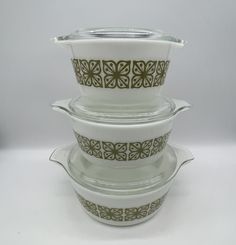 three white dishes stacked on top of each other with brown flower designs in the middle