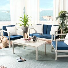 a living room filled with furniture and a large window overlooking the ocean on a sunny day