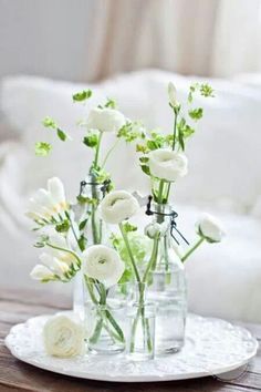 three vases with flowers in them sitting on a white doily near a couch