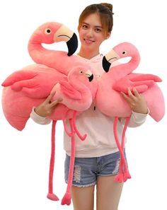 a girl holding three pink flamingos in her hands