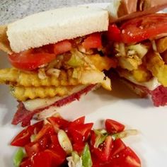 the sandwich is cut in half on the plate with tomatoes and lettuce next to it