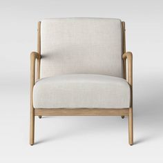 a white chair sitting on top of a gray floor next to a wooden frame and armrest