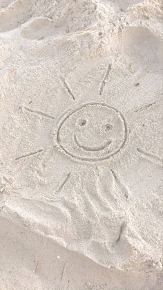 a smiley face drawn in the sand on a beach