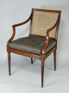 an antique chair with caned back and arm rests against a white background in the image