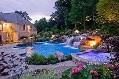 a backyard with a pool and waterfall at night