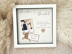 a white frame with two pictures and a heart hanging from the side on a furry surface