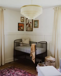 a baby crib in the corner of a room with pictures hanging on the wall