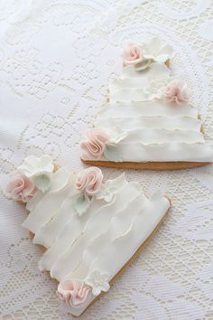 two cookies decorated with white icing and pink flowers on top of a tablecloth