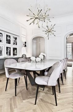 a dining room table with chairs and pictures on the wall behind it in an elegant style