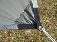 a close up view of the side of a tent with straps attached to it and grass in the background