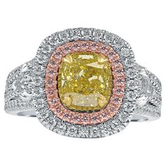 This stunning engagement ring showcases a breathtaking 1.27-carat GIA Certified cushion brilliant cut natural fancy vivid yellow diamond at its center. With its I2 clarity, this vibrant yellow diamond is a rare treasure, surrounded by a mesmerizing double halo of pink and colorless round cut diamonds, all meticulously set in a micro pavé arrangement. The diamonds in the halo feature G/H color and VS/SI clarity, enhancing the ring's brilliance and allure. The ring’s design is further elevated by a triple split shank adorned with two shield-cut side diamonds, totaling 0.43 carats, also in G/H color and VS/SI clarity. These side diamonds add a striking dimension to the ring, making it truly unforgettable. Handcrafted in luxurious 18-karat multi-tone gold, this piece is a masterpiece of artist Engagement Ring Pink Diamond, Engagement Ring Pink, Antique Cushion Cut Diamond, Radiant Diamond Engagement Rings, Cushion Cut Diamond Engagement Ring, Yellow Diamonds Engagement, Yellow Diamond Engagement Ring, Platinum Diamond Engagement Rings, Yellow Diamond Rings