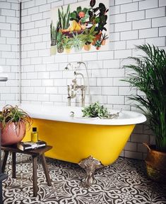 a yellow bath tub sitting next to a green plant in a white tiled bathroom with potted plants on the floor