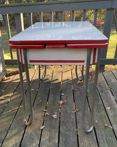 a red and white table sitting on top of a wooden deck