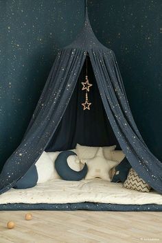 a child's bed with stars on the wall and blue curtains hanging from it