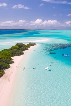 an aerial view of people on the beach and in the water, with small boats