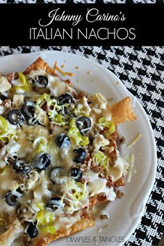 a white plate topped with pizza covered in cheese and olives next to tortilla chips