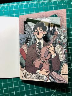 an open book with a drawing of a man holding a violin on top of it