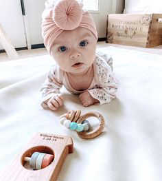 a baby laying on the floor next to some wooden beads and a pacifier in it's mouth