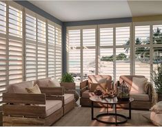 a living room filled with furniture and large windows covered in shuttered glass doors that look out onto the ocean