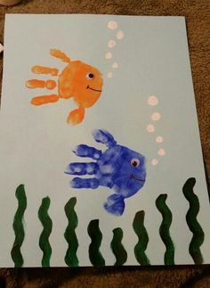 a child's handprinted picture of a fish and an orange fish in the water