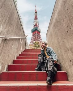 a man is sitting on the stairs in front of the eiffel tower