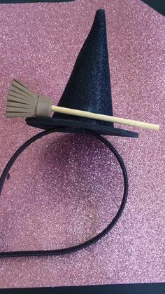 a witches hat with a broom on it sitting on top of a pink tablecloth