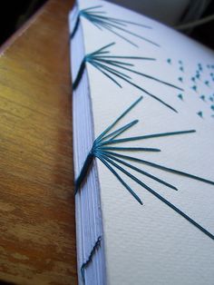 a piece of paper with blue thread on it sitting on top of a wooden table