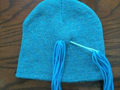 a blue knitted hat with tassels sitting on top of a wooden table