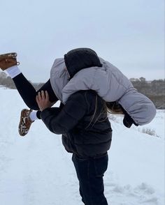 a woman walking in the snow carrying a child on her back with one foot up