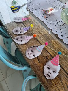 a wooden table topped with paper cut out of baby's face and balloons on top of it