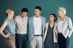 a group of people standing next to each other in front of a green wall smiling